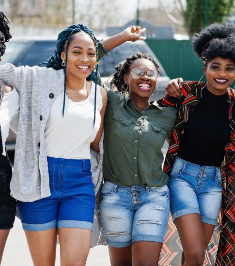 Group of five african american woman walking on road together against suv car on parking.